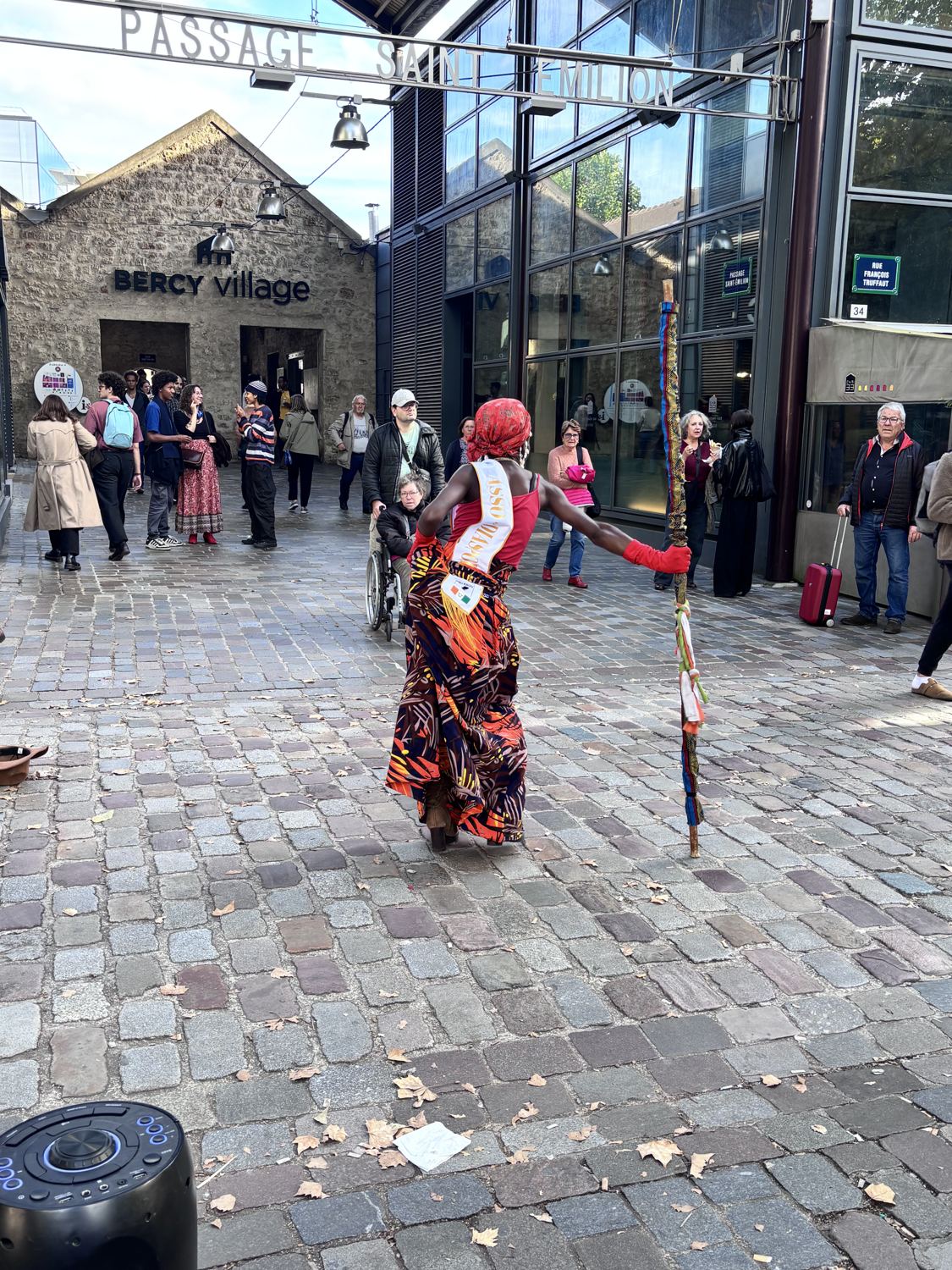 Kemet de dos, bâton tendu, devant le public du passage Saint-Émilion