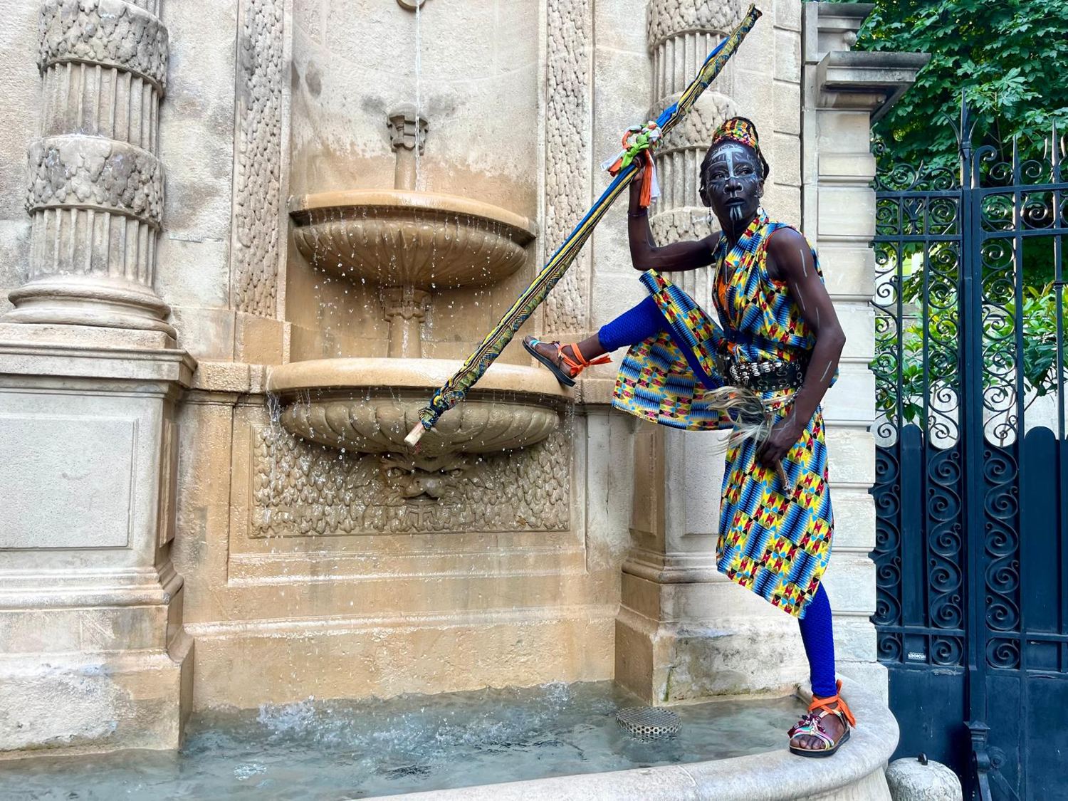 Kemet, jambe levée, bâton dressé devant une fontaine