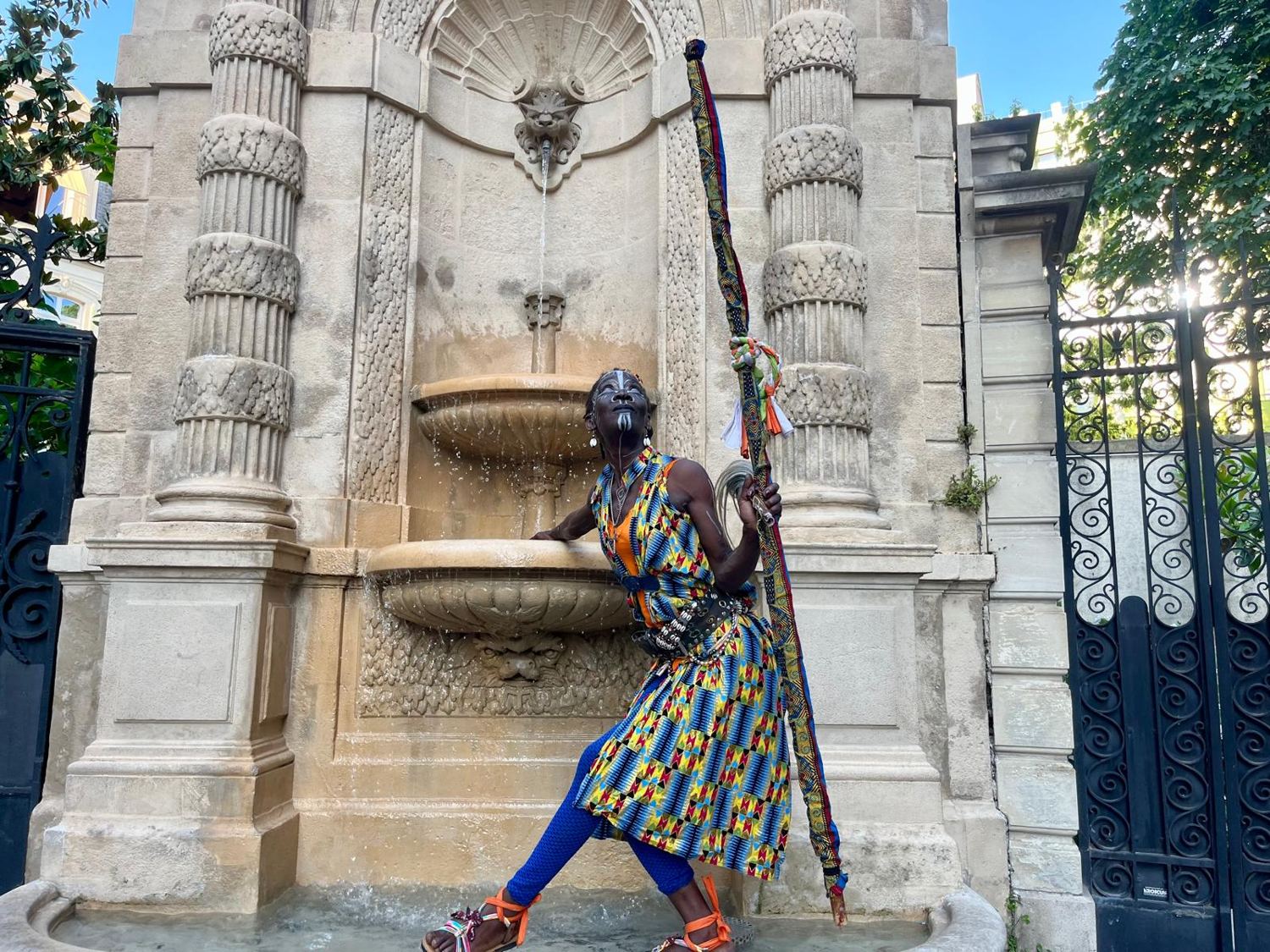 Kemet debout dans la vasque d'une fontaine, bâton à la main